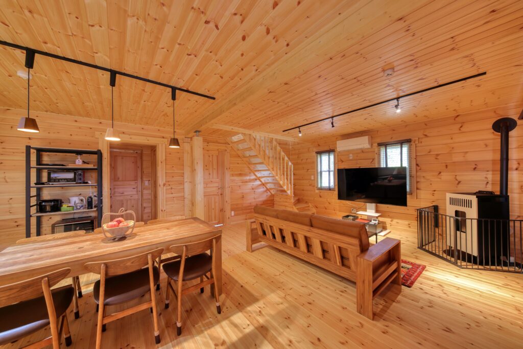 木の壁と大きなテーブルのあるThe appleのリビング・ダイニング