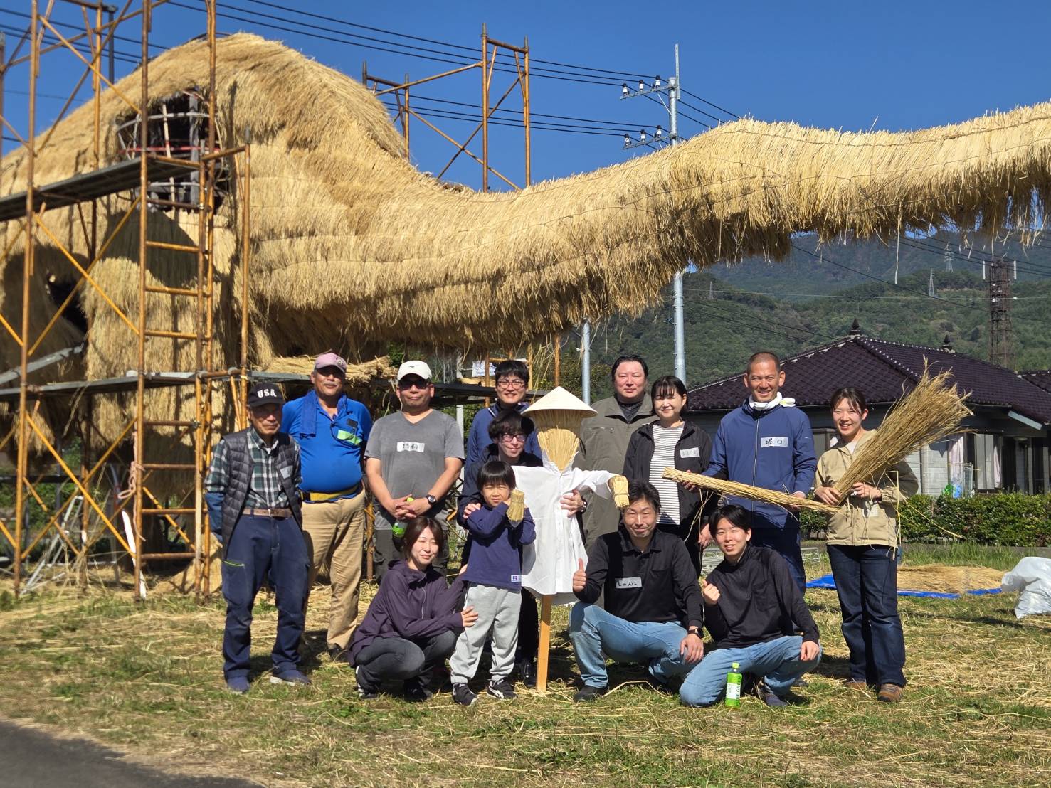 制作途中の迷惑龍とかかしの前に集まる協働制作の参加者